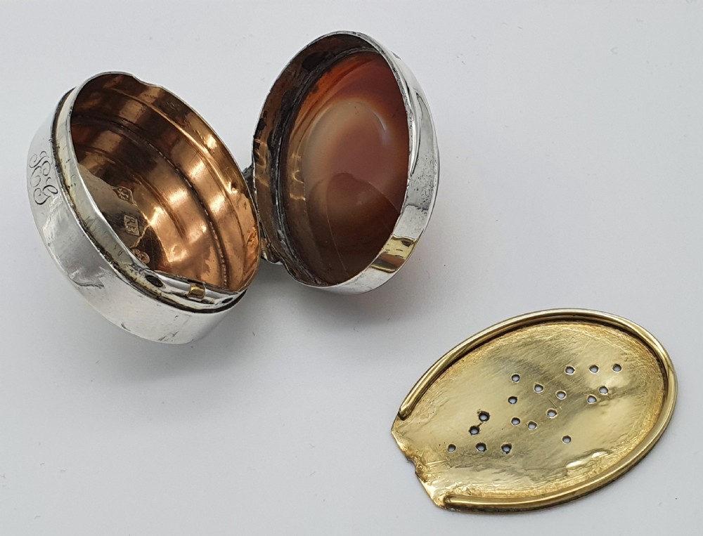 A Georgian oval silver vinaigrette featuring a smooth brown agate top and engraved script monogram on the silver collar. View XI
