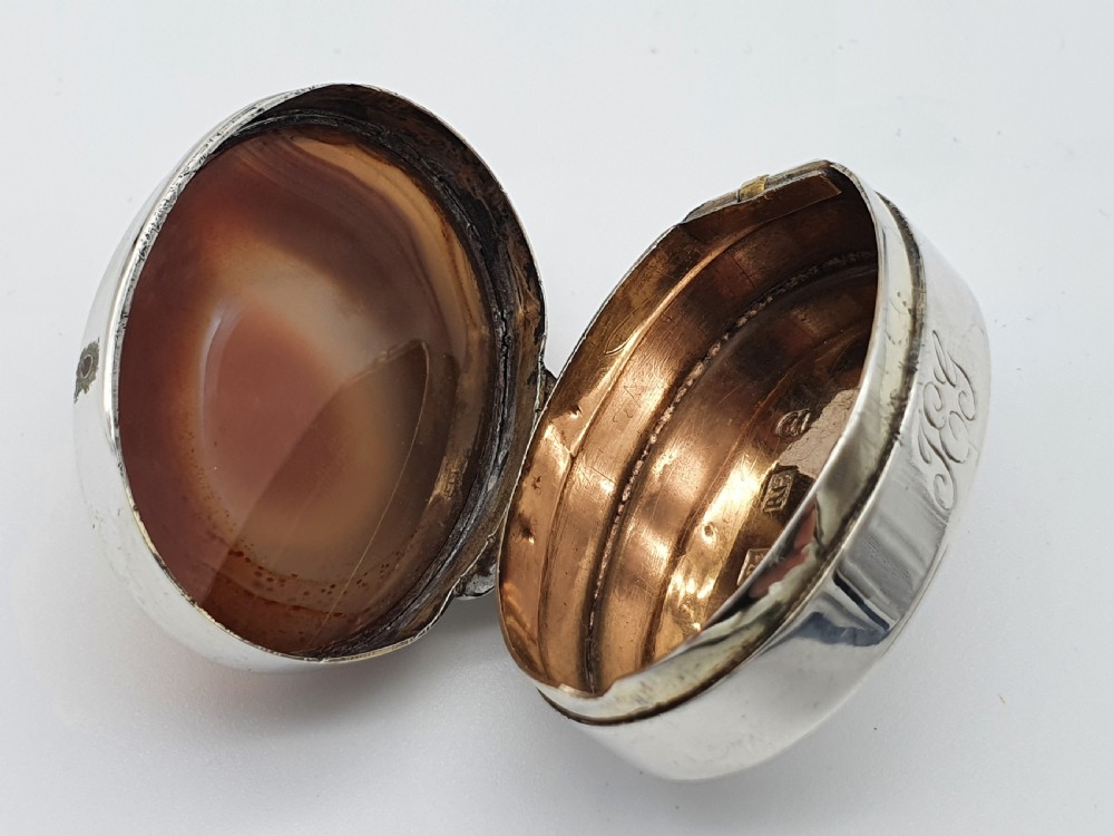 A Georgian oval silver vinaigrette featuring a smooth brown agate top and engraved script monogram on the silver collar. View XIV