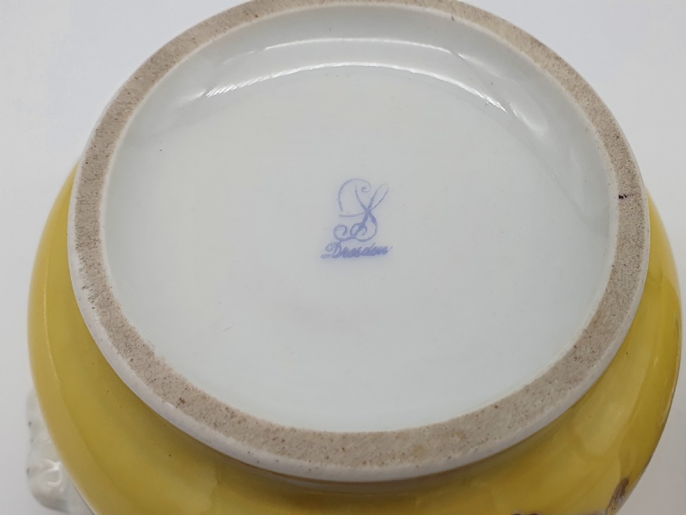 A yellow and white Dresden porcelain cache pot featuring side handles, gold gilding, and a central cartouche depicting a purple painted pastoral scene. View VIII