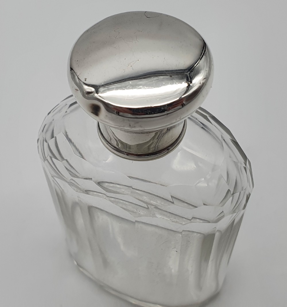A George V clear faceted glass bottle featuring a hallmarked sterling silver collar and polished silver top cap. View VI