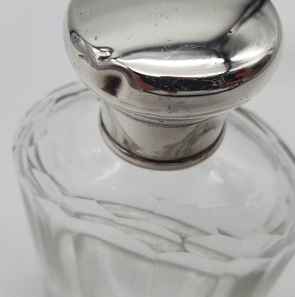 A George V clear faceted glass bottle featuring a hallmarked sterling silver collar and polished silver top cap. View VII