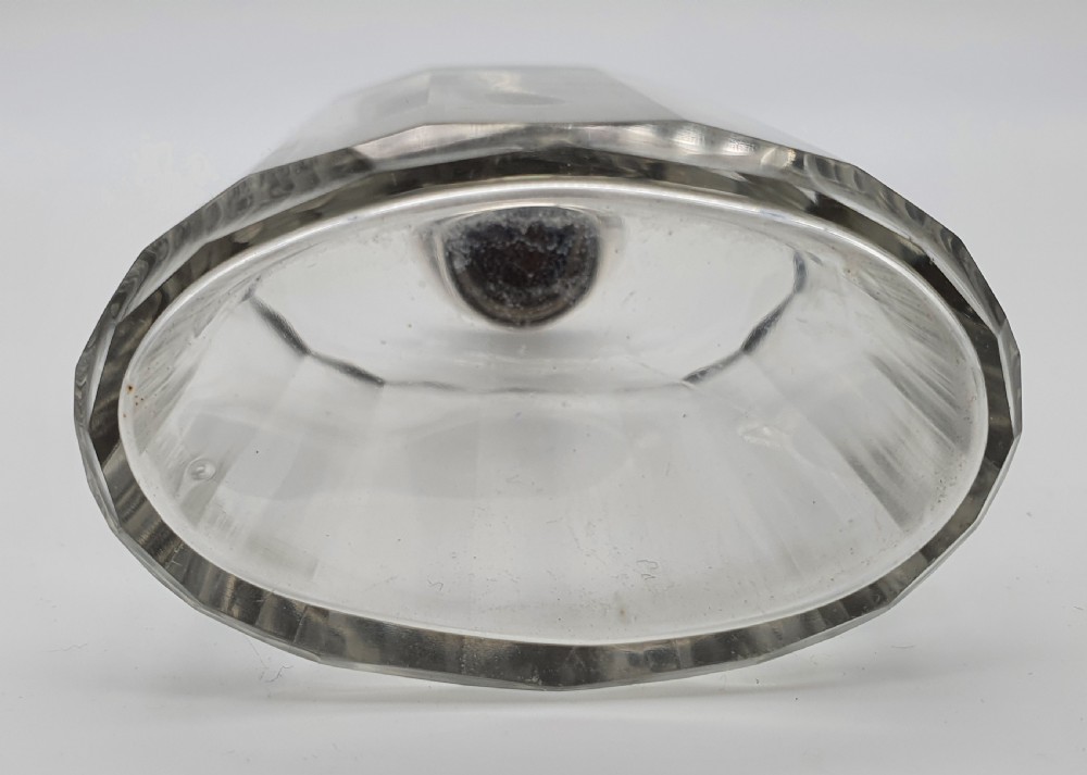 A George V clear faceted glass bottle featuring a hallmarked sterling silver collar and polished silver top cap. View VIII