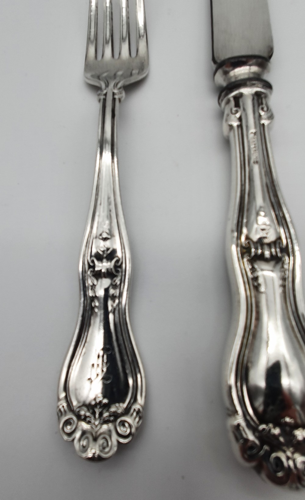 An American sterling silver table knife and matching four-tined fork featuring ornate foliate scrollwork handles. View II