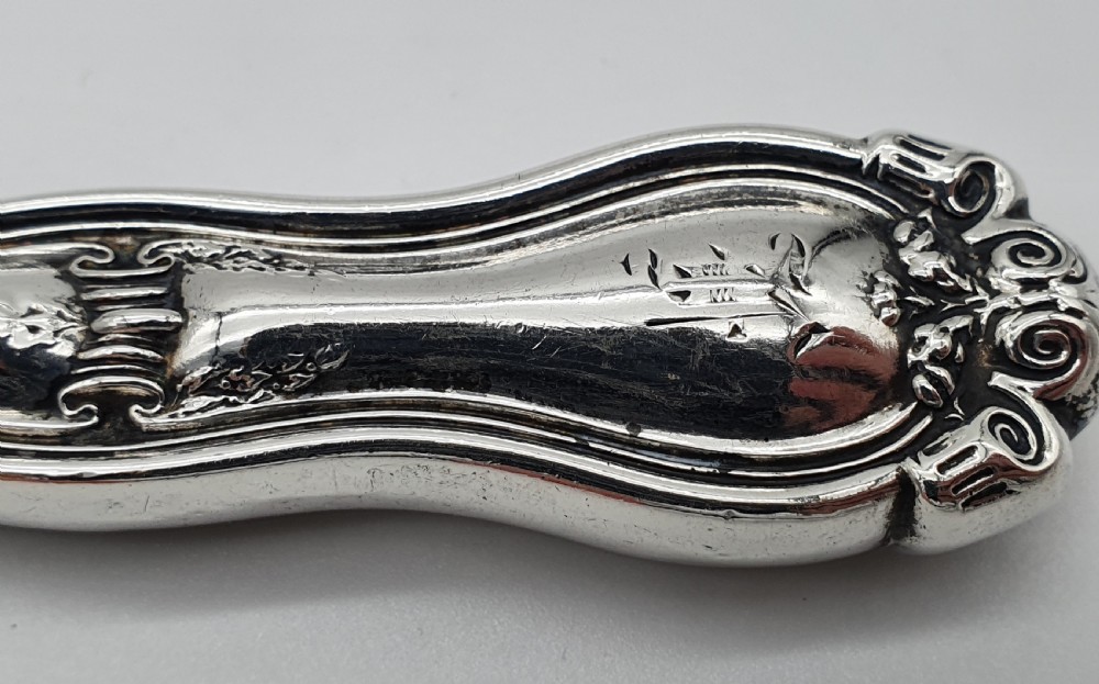 An American sterling silver table knife and matching four-tined fork featuring ornate foliate scrollwork handles. View IX