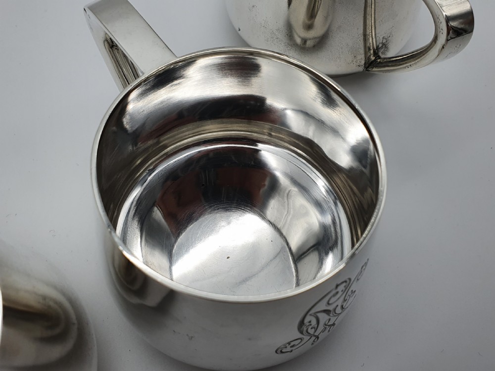 A set of four small silver vodka cups with angular handles and engraved monograms against a white backdrop. View VIII
