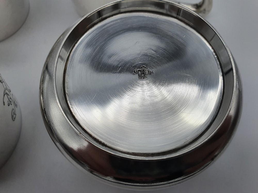 A set of four small silver vodka cups with angular handles and engraved monograms against a white backdrop. View XIII