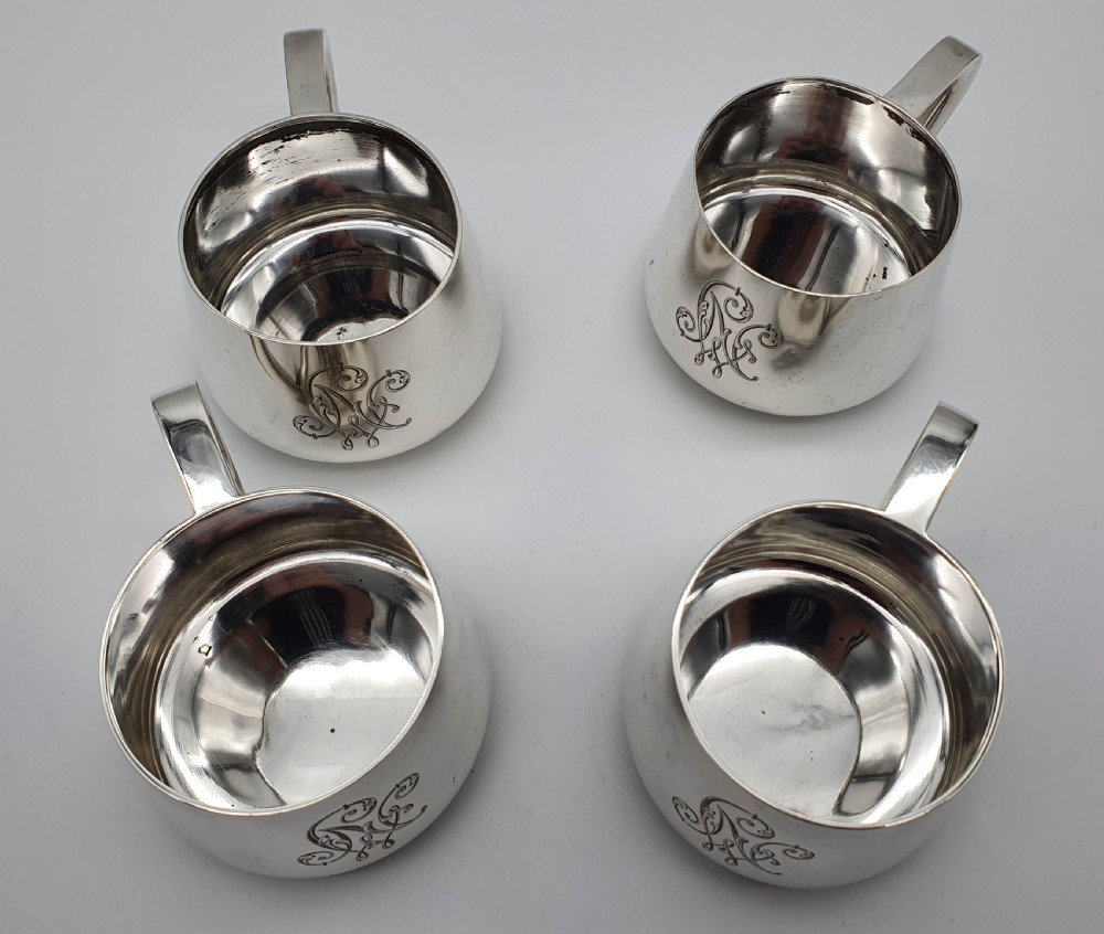A set of four small silver vodka cups with angular handles and engraved monograms against a white backdrop. View XVIII