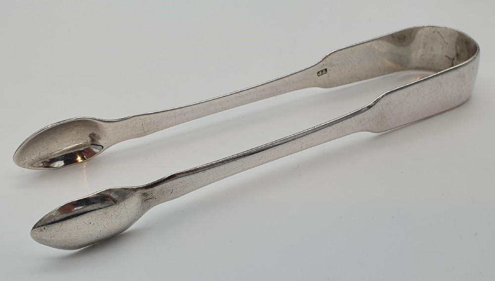 A pair of George III sterling silver sugar tongs featuring smooth spoon-shaped bowls and a curved bow hinge with makers mark TP.