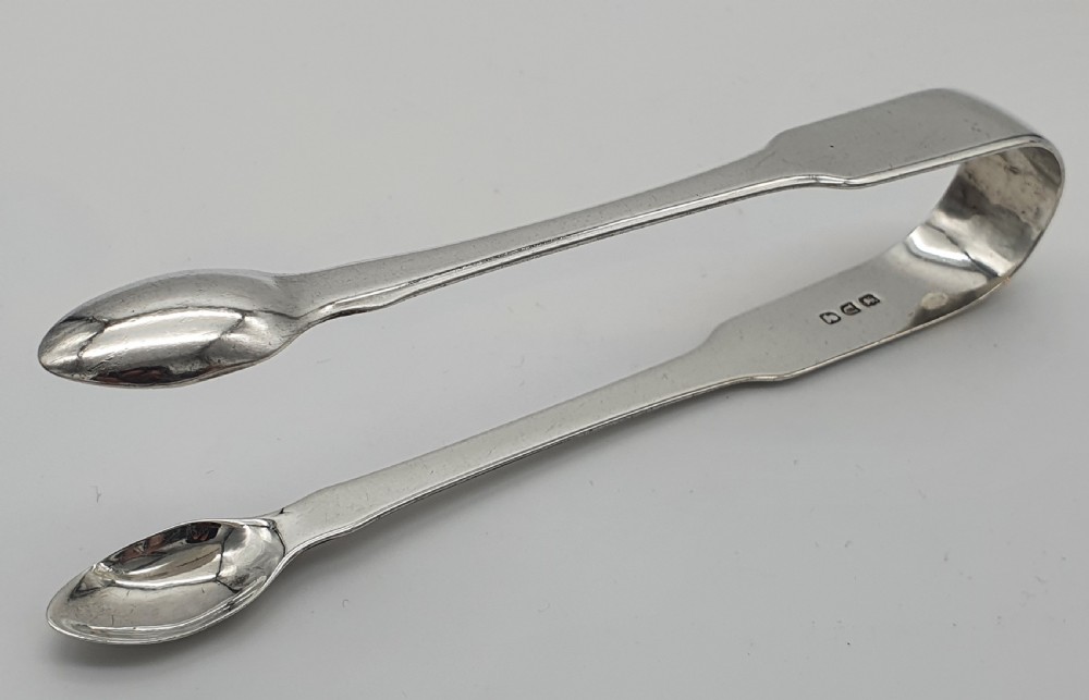 A pair of George III sterling silver sugar tongs featuring smooth spoon-shaped bowls and a curved bow hinge with makers mark TP. View II