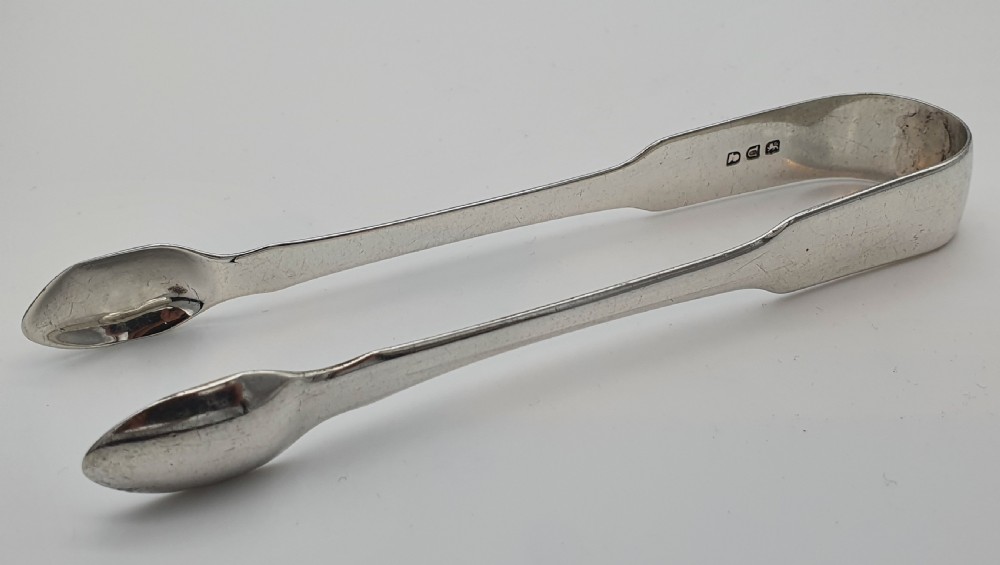 A pair of George III sterling silver sugar tongs featuring smooth spoon-shaped bowls and a curved bow hinge with makers mark TP. View V