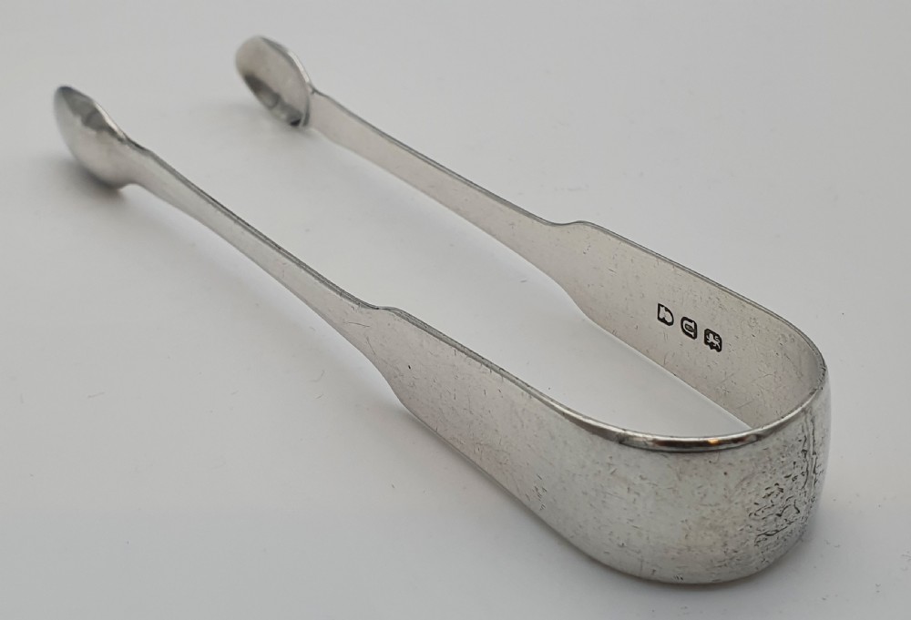 A pair of George III sterling silver sugar tongs featuring smooth spoon-shaped bowls and a curved bow hinge with makers mark TP. View VI