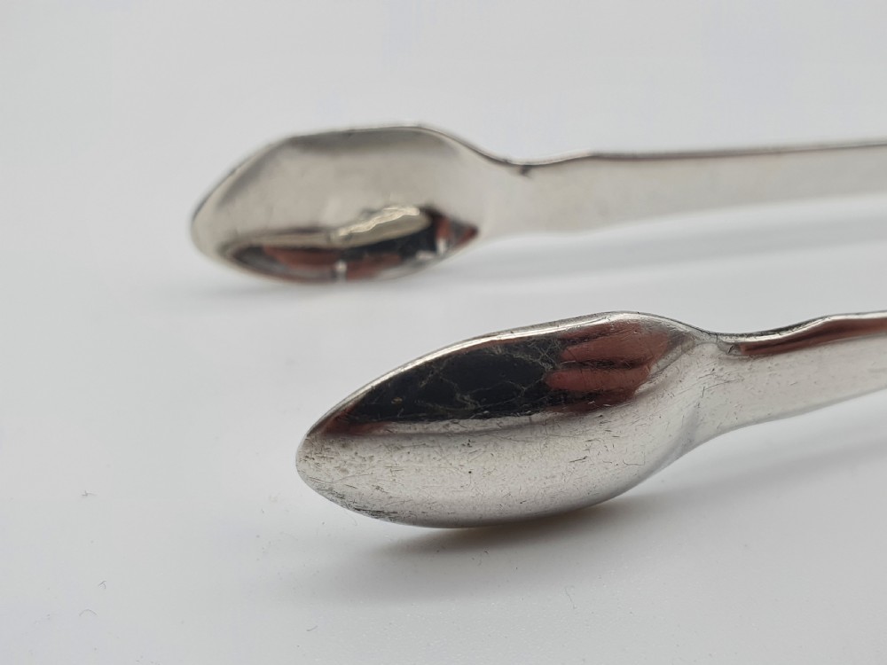 A pair of George III sterling silver sugar tongs featuring smooth spoon-shaped bowls and a curved bow hinge with makers mark TP. View XI