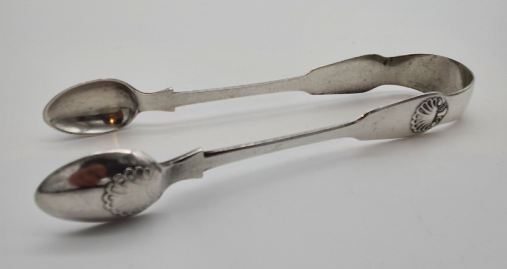 A pair of Victorian silver sugar tongs featuring shell motifs and spoon-shaped grips.