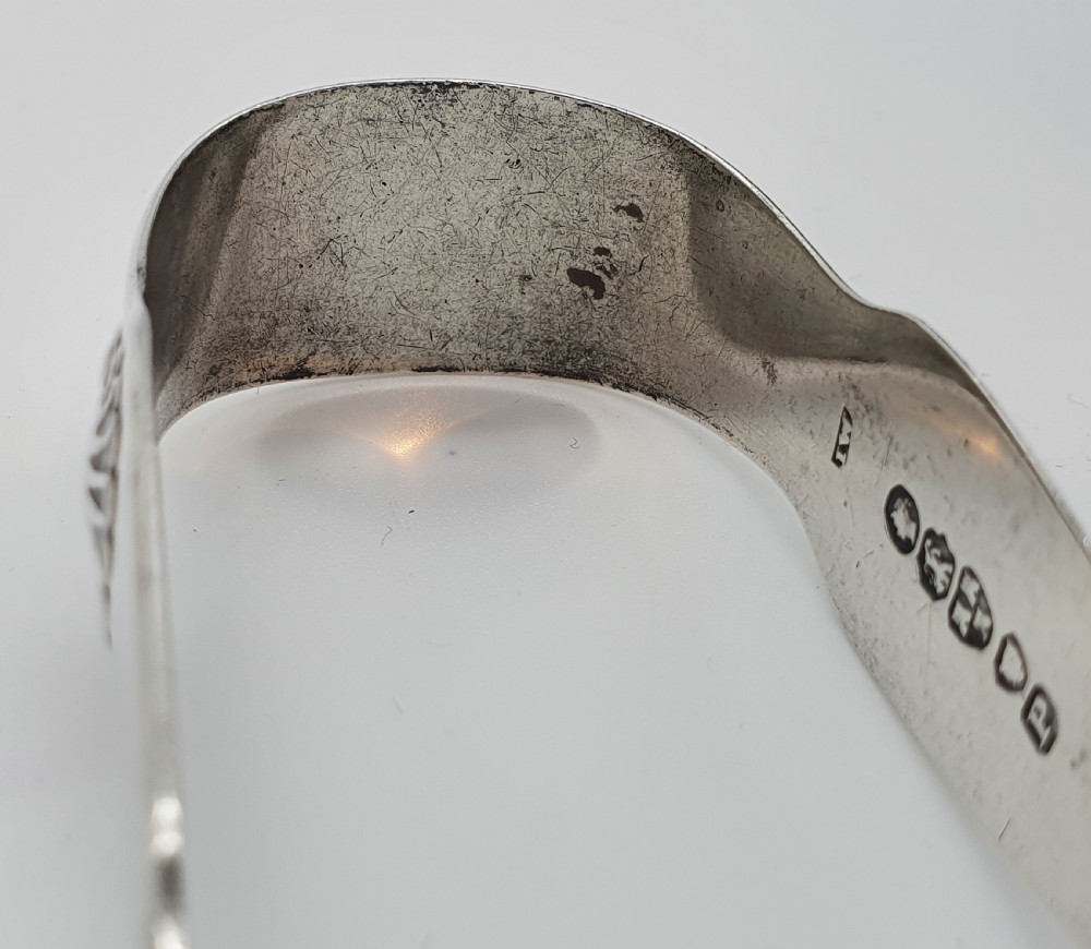 A pair of Victorian silver sugar tongs featuring shell motifs and spoon-shaped grips. View V