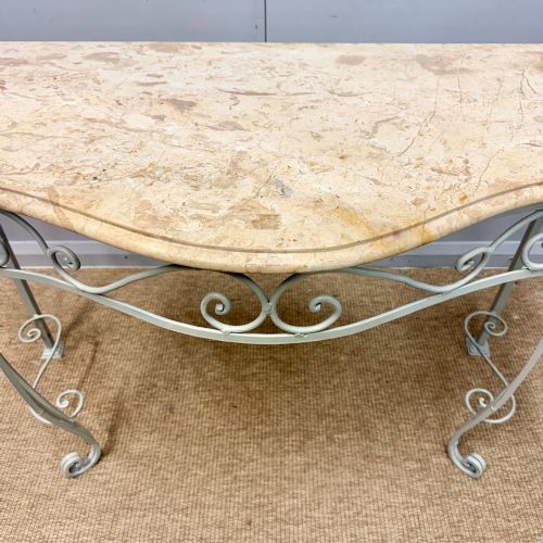 fig 1. A French wrought iron console table featuring a contoured beige marble top set upon an off-white painted frame with decorative scrollwork.