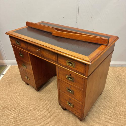 fig 1. A Victorian military campaign kneehole desk in warm brown wood, featuring an inset leather writing surface, gallery rail, and seven drawers with flush brass handles.