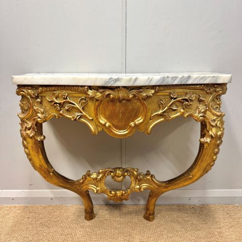 fig 1. A French Louis XV style giltwood console table with heavily carved Rococo scrollwork, cabriole legs, and a white veined marble top.