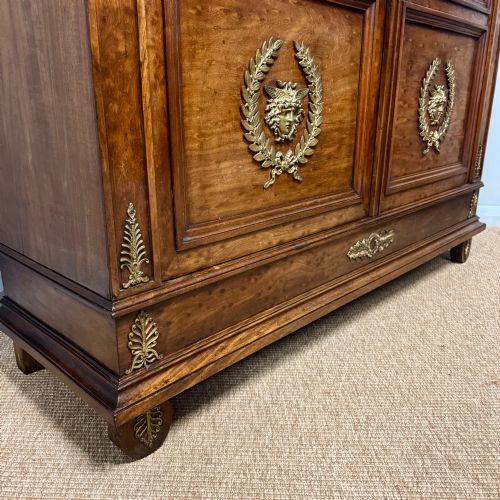 fig 2. A tall French Empire style warm brown timber bookcase featuring two glass-fronted doors, gilt brass laurel wreath mounts, and adjustable interior shelves.