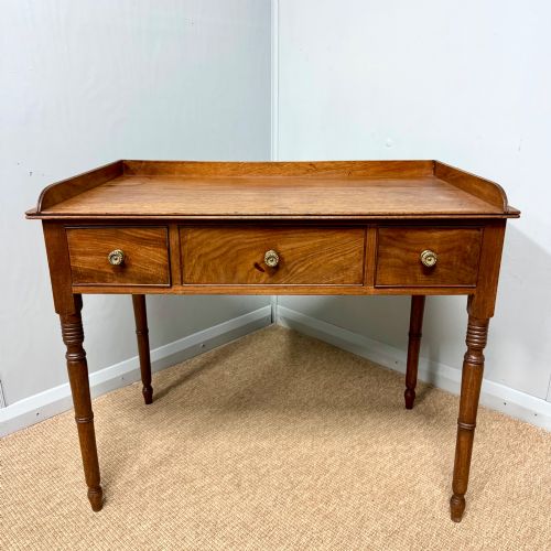 fig 1. A Regency mahogany dressing table featuring three drawers with round brass knobs, a raised gallery top, and four turned tapered legs.