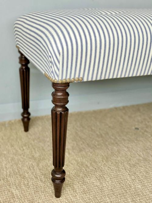 fig 1. A pair of long upholstered benches featuring grey and white striped ticking fabric with deep button tufting set upon dark turned and fluted timber legs.