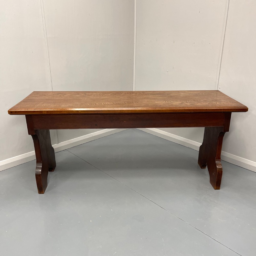 A long, solid oak altar table featuring a smooth rectangular top surface resting on two shaped slab end legs.