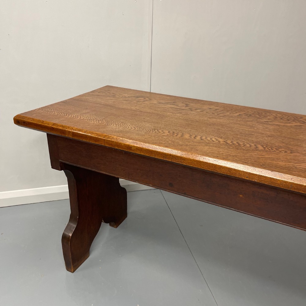 A long, solid oak altar table featuring a smooth rectangular top surface resting on two shaped slab end legs. View II