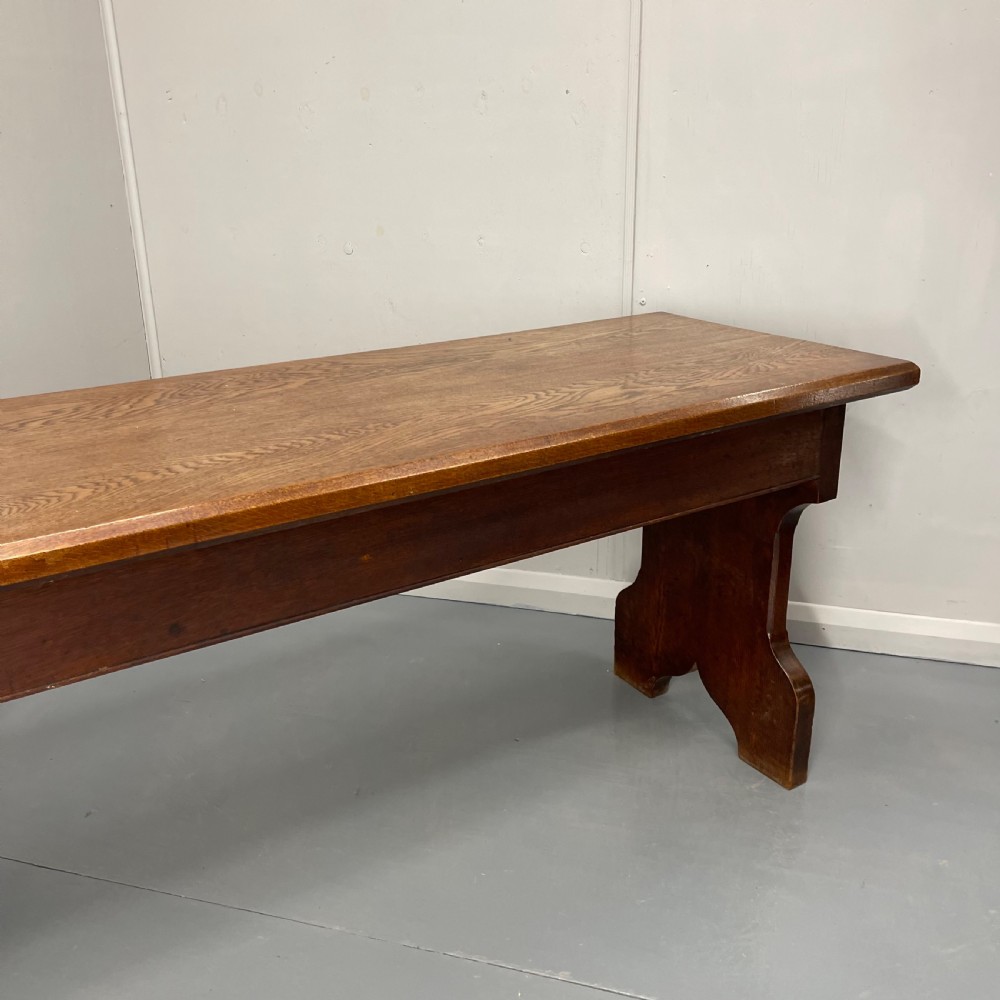 A long, solid oak altar table featuring a smooth rectangular top surface resting on two shaped slab end legs. View III