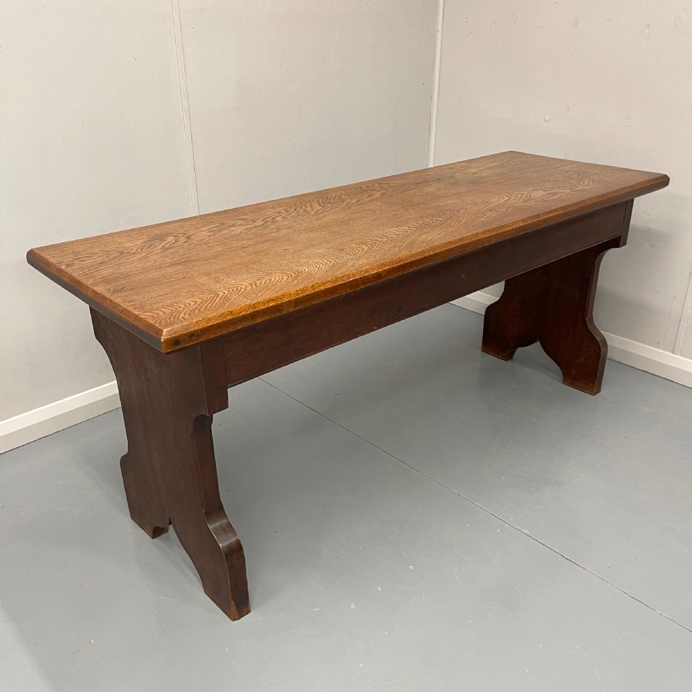 A long, solid oak altar table featuring a smooth rectangular top surface resting on two shaped slab end legs. View V