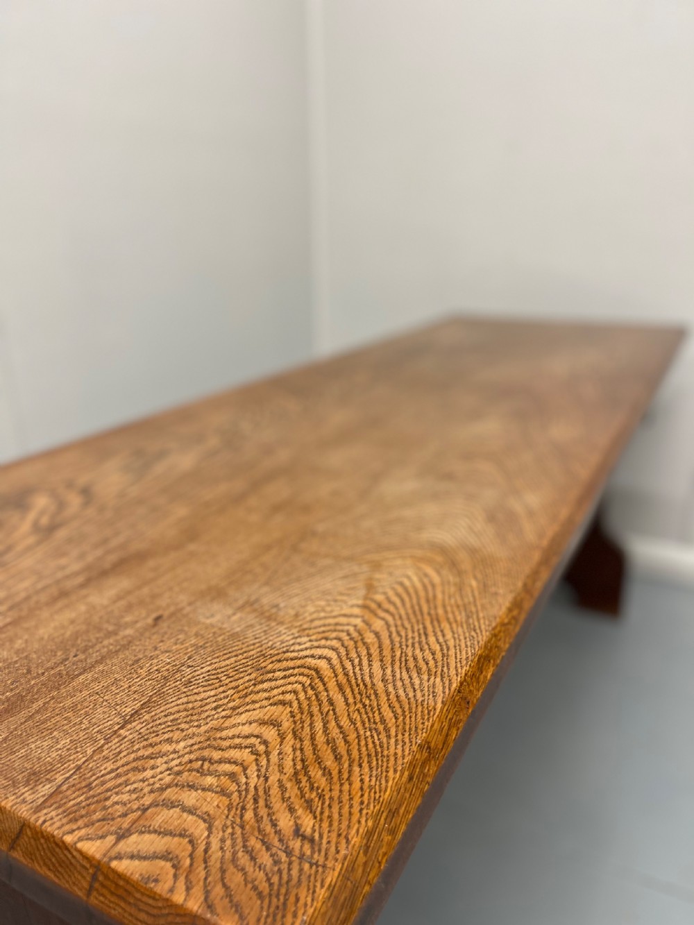 A long, solid oak altar table featuring a smooth rectangular top surface resting on two shaped slab end legs. View VI
