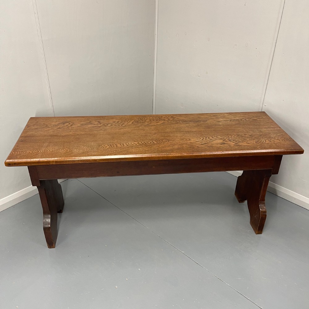 A long, solid oak altar table featuring a smooth rectangular top surface resting on two shaped slab end legs. View VII