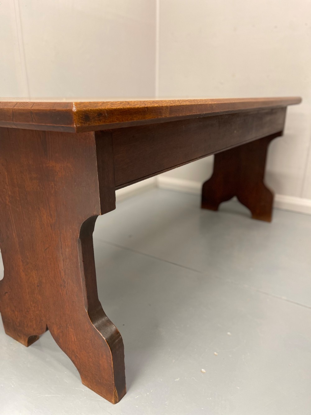 A long, solid oak altar table featuring a smooth rectangular top surface resting on two shaped slab end legs. View VIII