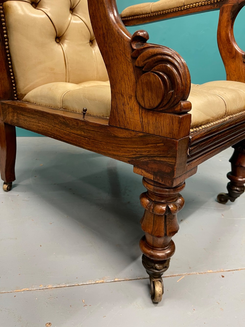 A Late Regency mahogany reclining armchair featuring buttoned tan leather upholstery, brass stud trim, scroll arms, and turned front legs on castors. View VIII