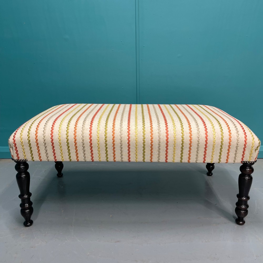 Newly upholstered ottoman stool on ebonised legs 