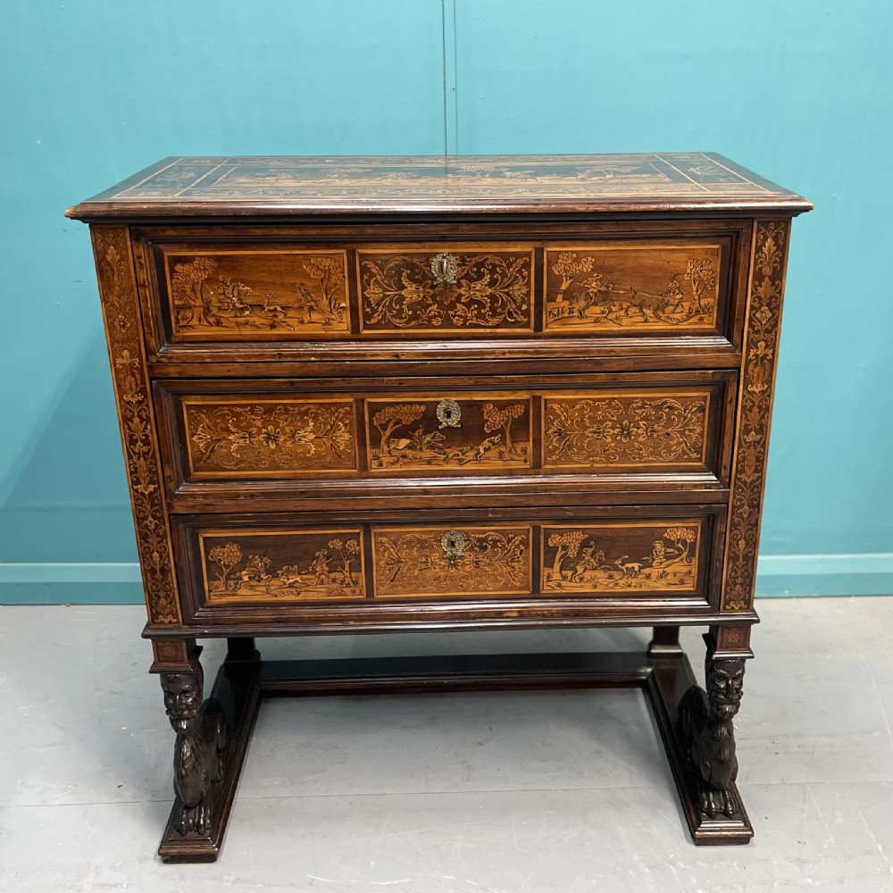 A nineteenth-century Italian walnut chest featuring three drawers decorated with detailed marquetry pictorial scenes and resting on carved base supports.