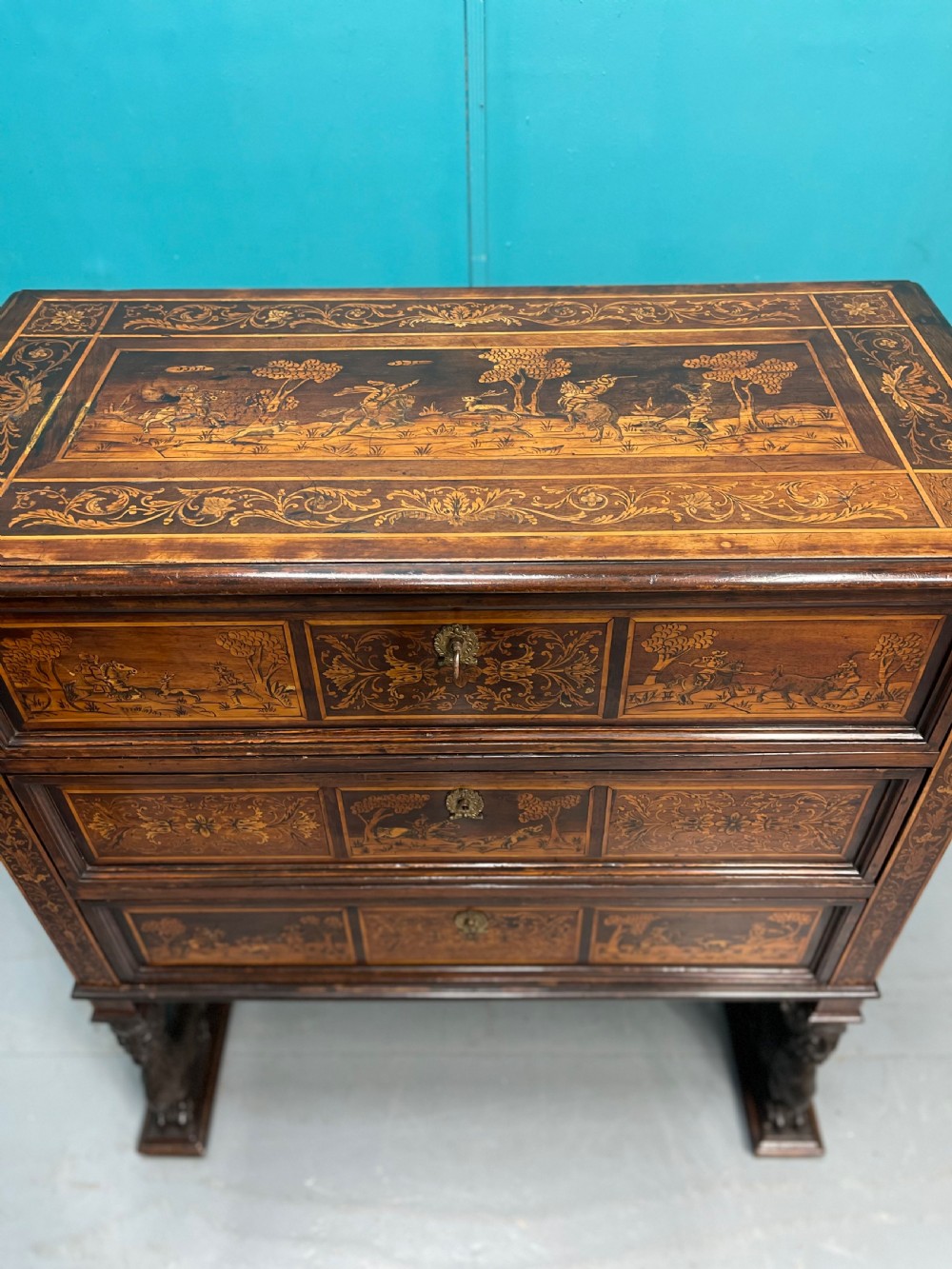 A nineteenth-century Italian walnut chest featuring three drawers decorated with detailed marquetry pictorial scenes and resting on carved base supports. View V
