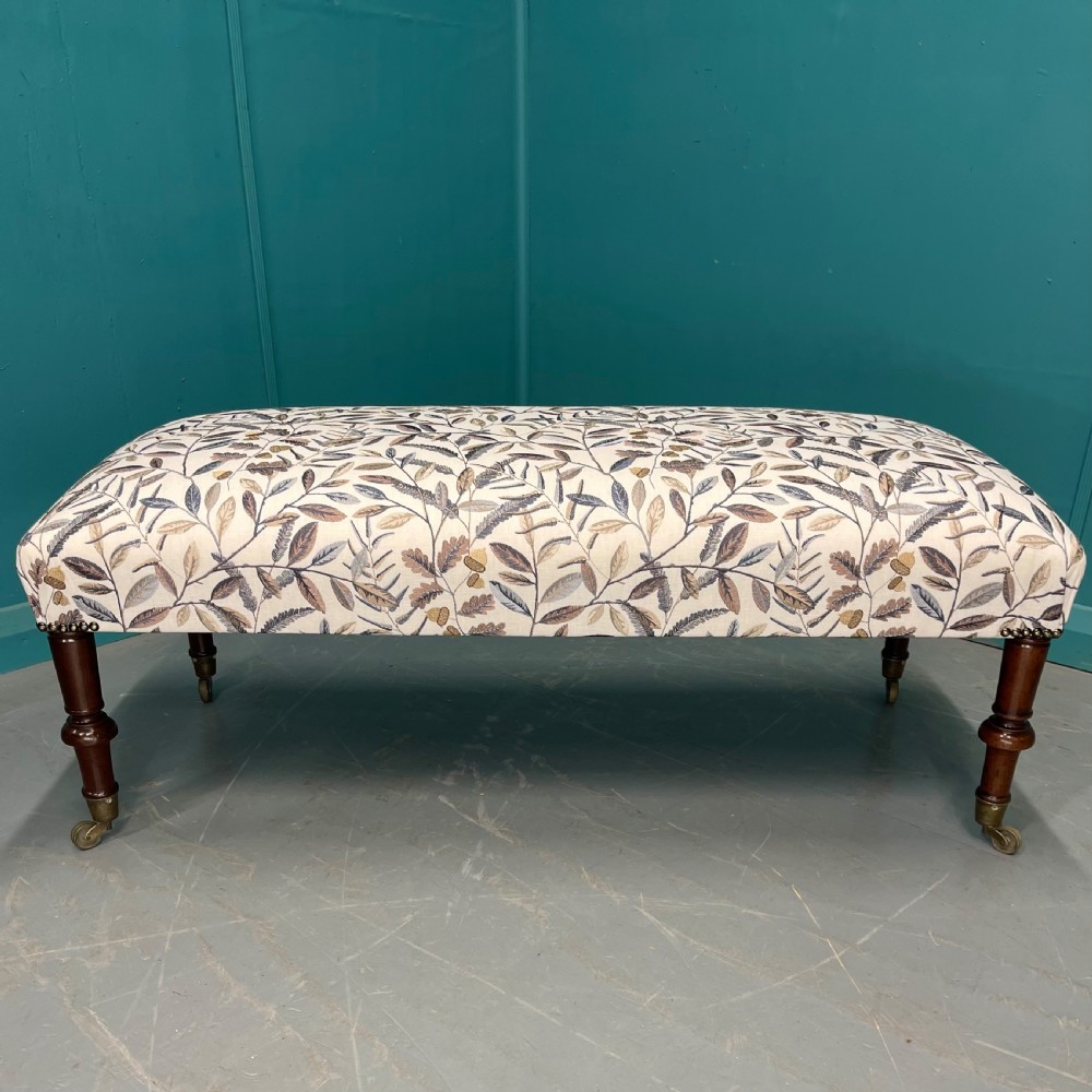 Newly upholstered leaf motif footstool on castors View II