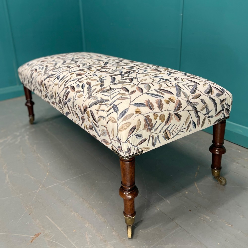 Newly upholstered leaf motif footstool on castors