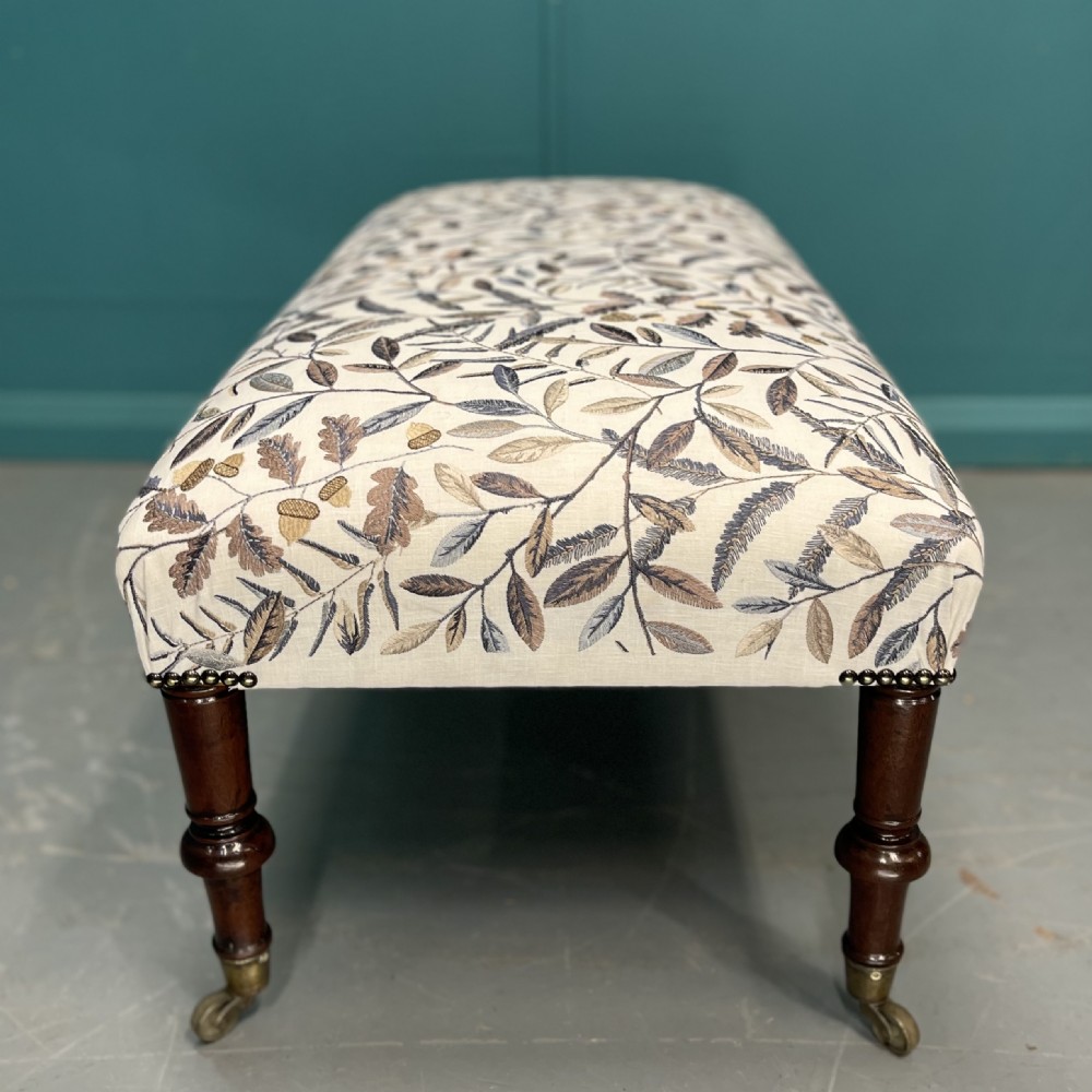 Newly upholstered leaf motif footstool on castors View VI