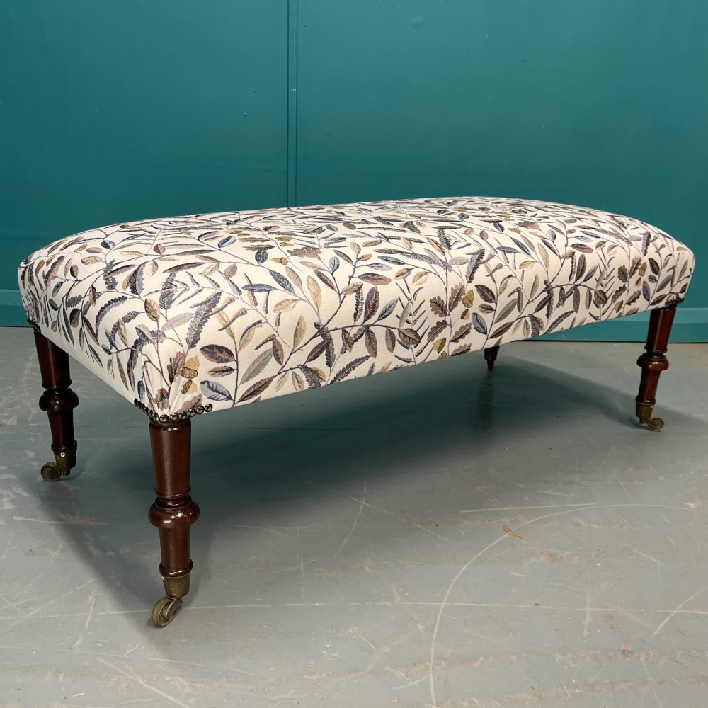 Newly upholstered leaf motif footstool on castors View VII