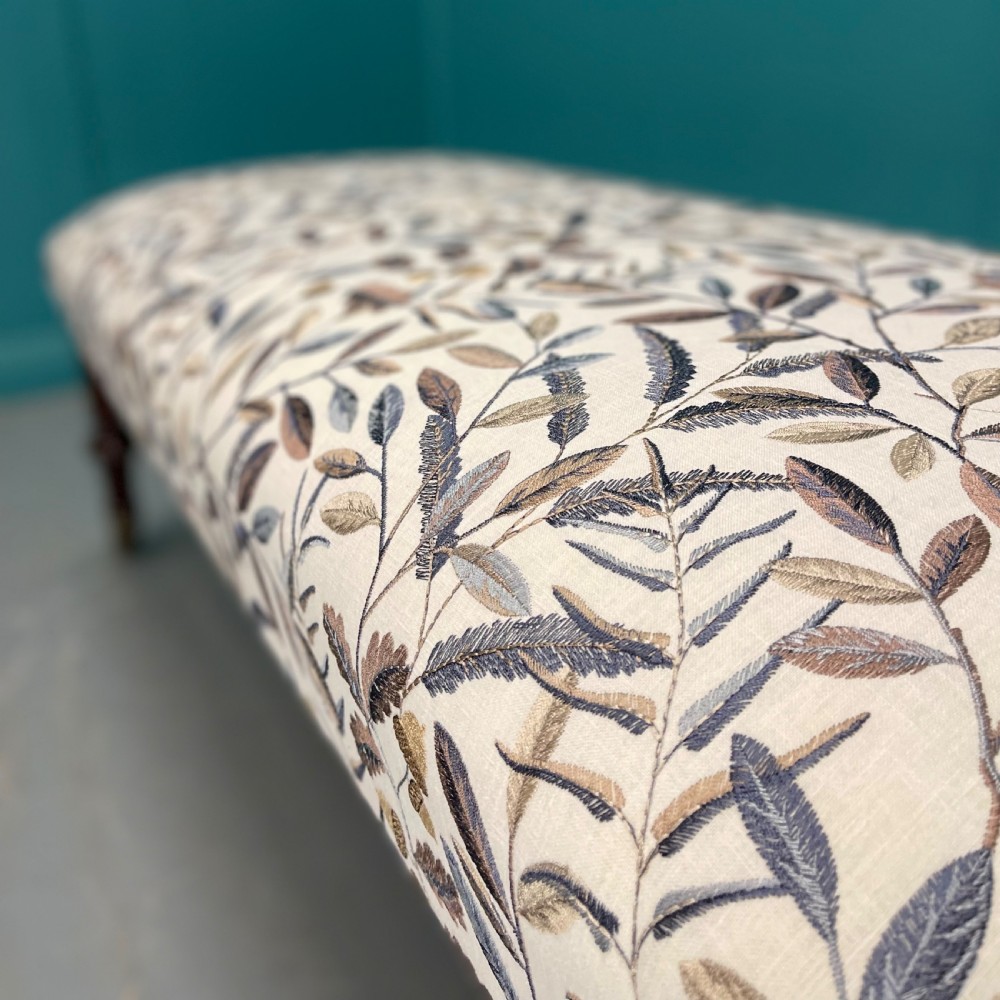 Newly upholstered leaf motif footstool on castors View VIII