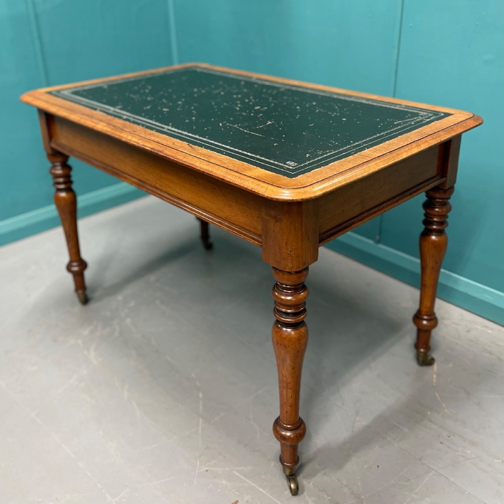 A rectangular Victorian timber library table featuring a green leather insert top with gold tooling, turned legs, and brass castors.