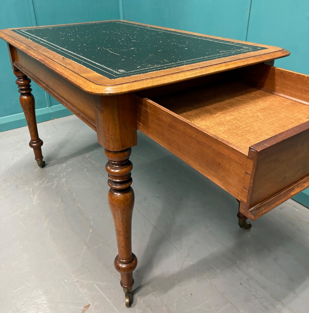 A rectangular Victorian timber library table featuring a green leather insert top with gold tooling, turned legs, and brass castors. View III