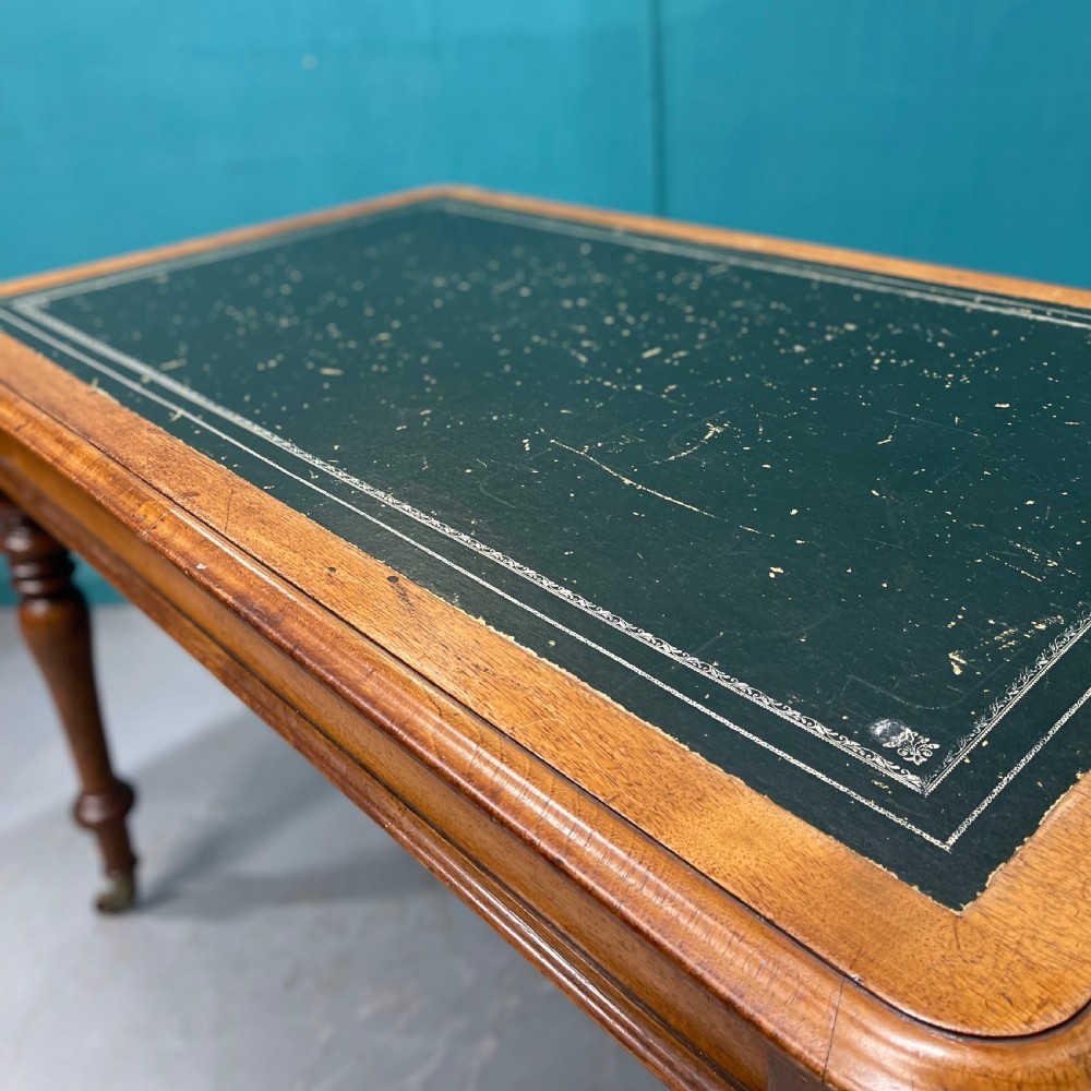 A rectangular Victorian timber library table featuring a green leather insert top with gold tooling, turned legs, and brass castors. View VI