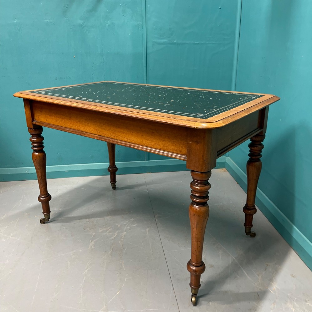 A rectangular Victorian timber library table featuring a green leather insert top with gold tooling, turned legs, and brass castors. View VIII