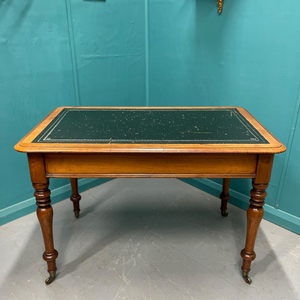 A rectangular Victorian timber library table featuring a green leather insert top with gold tooling, turned legs, and brass castors. View IX