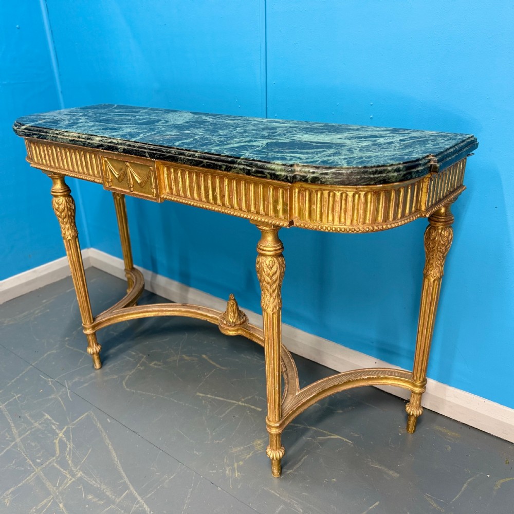An Adam style giltwood console table featuring a dark green marble top, fluted frieze with swag carvings, and slender tapered legs. View III