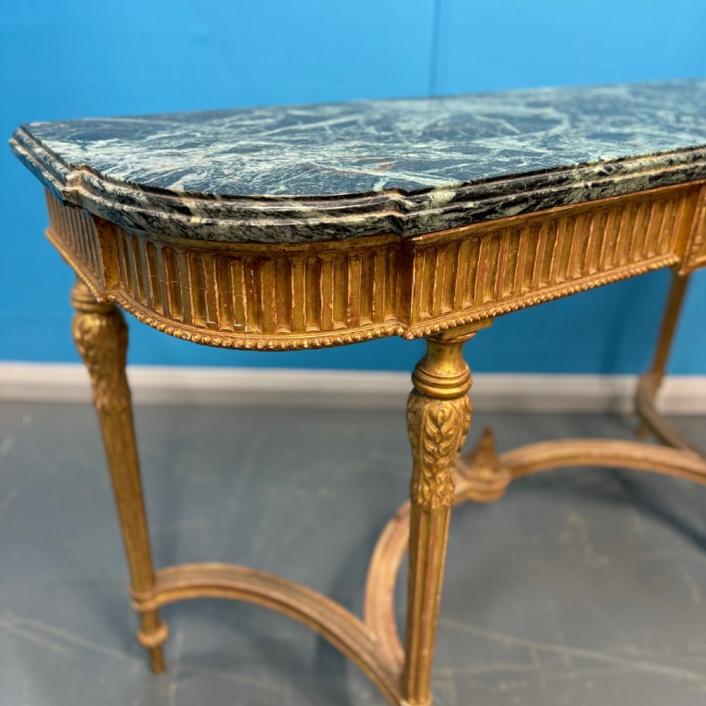 An Adam style giltwood console table featuring a dark green marble top, fluted frieze with swag carvings, and slender tapered legs. View V