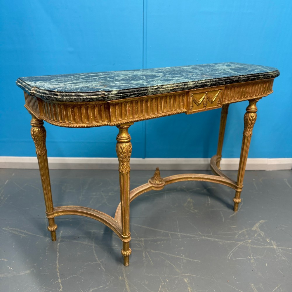 An Adam style giltwood console table featuring a dark green marble top, fluted frieze with swag carvings, and slender tapered legs. View VI