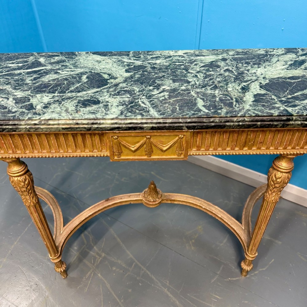 An Adam style giltwood console table featuring a dark green marble top, fluted frieze with swag carvings, and slender tapered legs. View VII