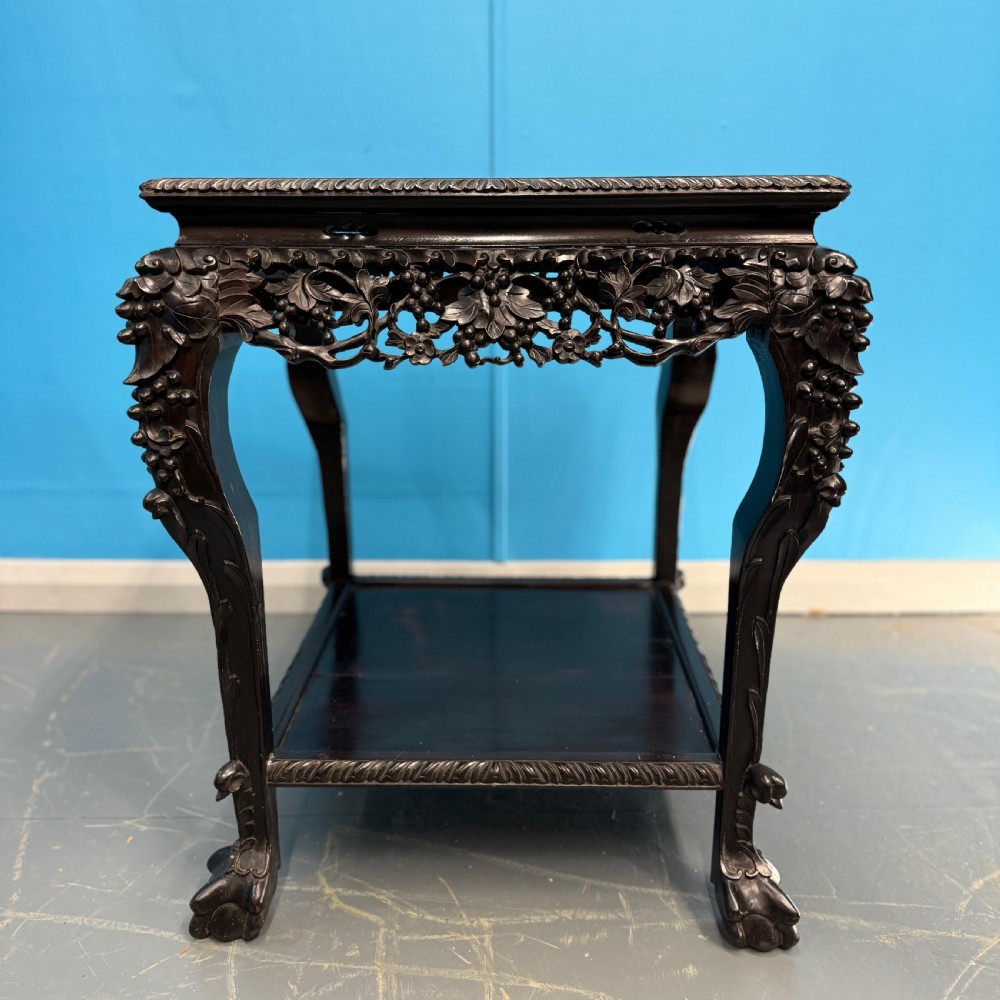 A dark carved Chinese hardwood side table with an inset pink marble top, openwork grapevine apron, cabriole legs, and a lower shelf. View II